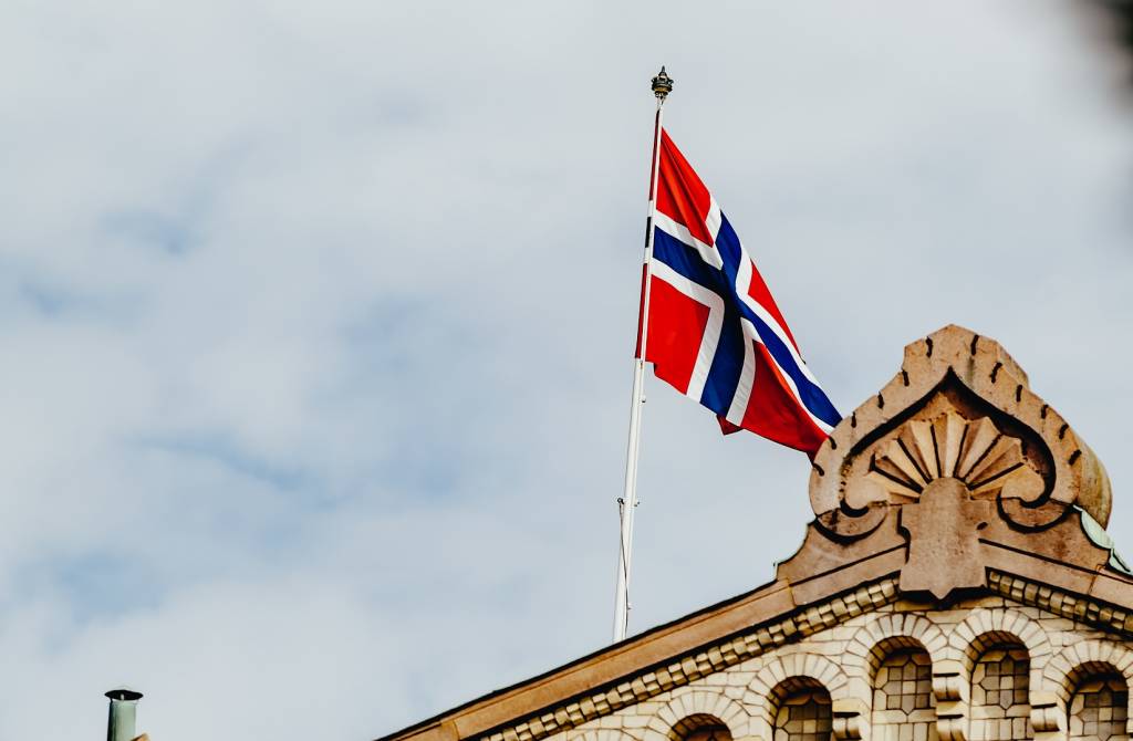 Himmel med norsk flagg og toppen av taket på Stortinget (foto)
