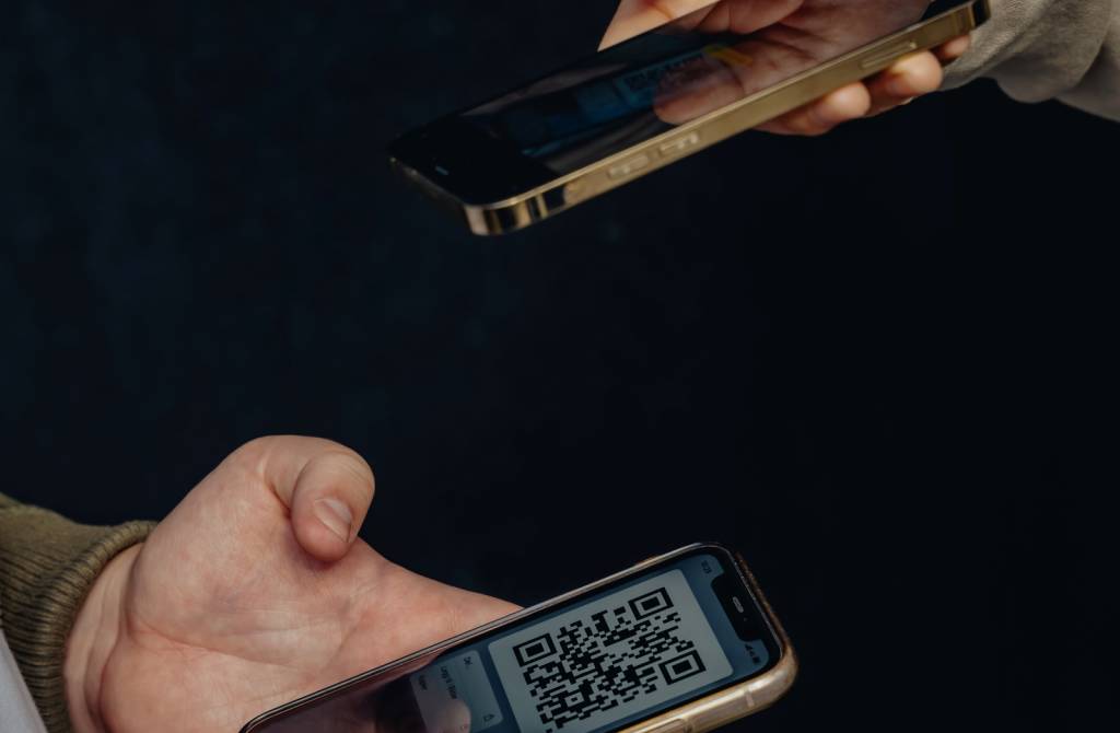 To mobiler holdes mot hverandre. Den ene mobilen tar bilde av en QR-kode som vises på den andre mobilen. (Foto)